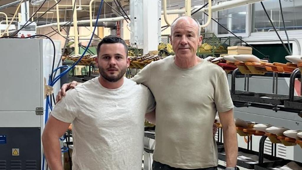 Padre e hijo posan en la fábrica de calzado en la que trabajan.