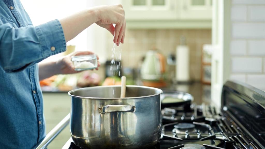 Una persona añadiendo sal a una olla. (Imagen de archivo)