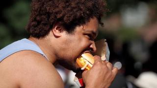 Hombre comiendo una hamburguesa en la calle.
