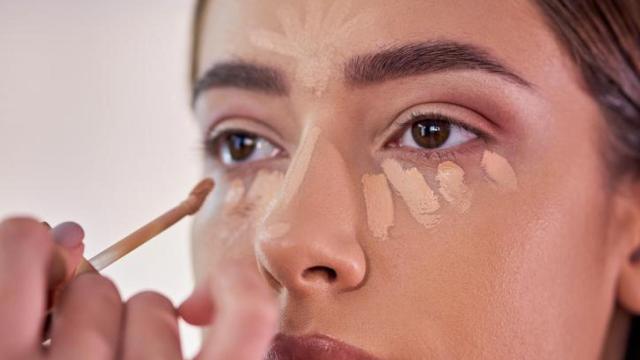 Mujer maquillándose con corrector de ojeras.