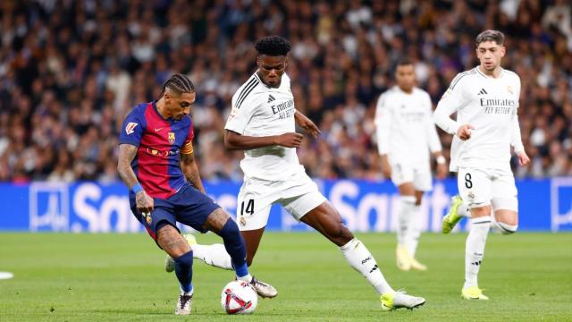 Raphinha retiene el balón ante la presión de Tchouaméni en el Clásico de La Liga.