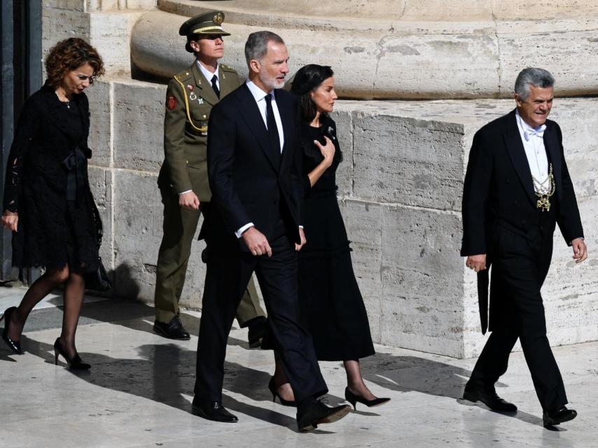 La Reina, de luto riguroso y con mantilla, del brazo del Rey, también de negro.