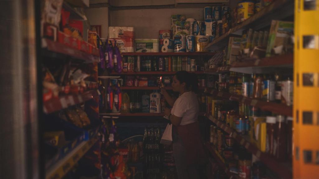 Una mujer haciendo la compra a oscuras a primera hora de la tarde del pasado lunes.