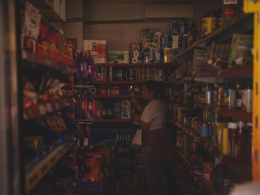 Una mujer haciendo la compra a oscuras a primera hora de la tarde del pasado lunes.