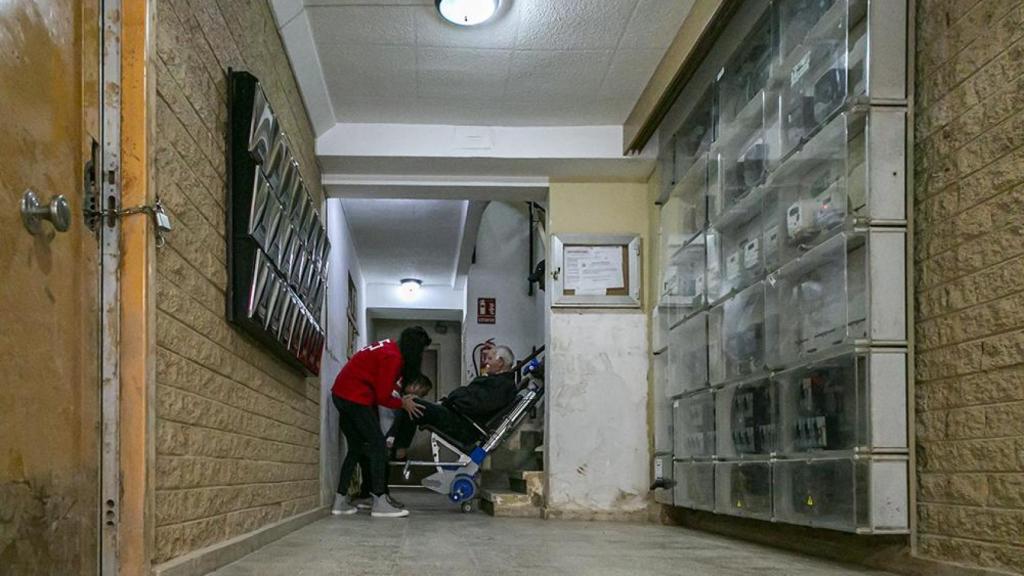 Cruz Roja baja de su casa a un vecino de Alfafar, con movilidad reducida y afectado por la dana, en una silla oruga. Toni Tomás