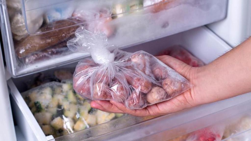 Mujer sacando comida del congelador.
