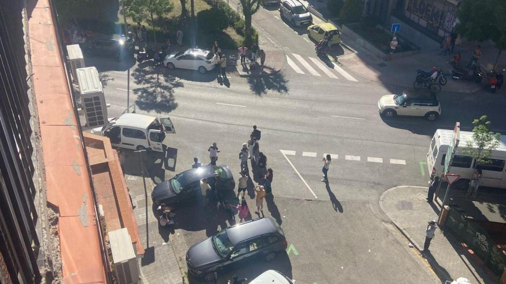 Vecinos congregados alrededor de un coche para escuchar la radio en Madrid.