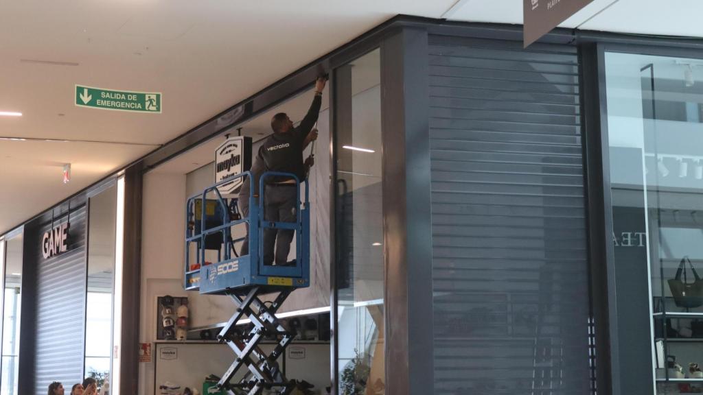 Un operario bajando la persiana de un negocio en Vigo tras el apagón