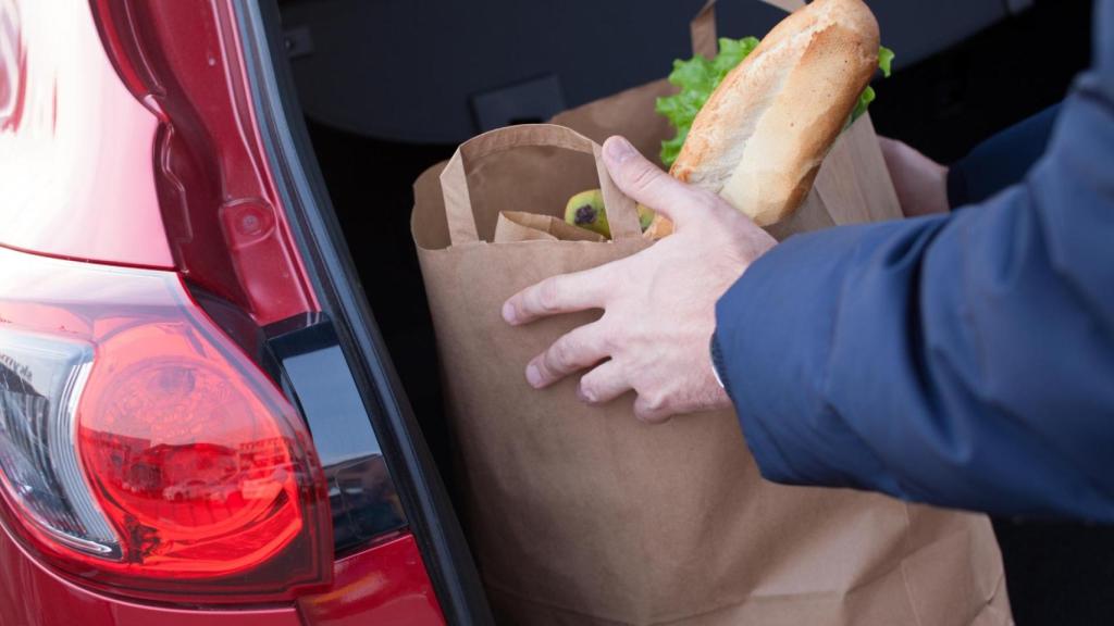 Una persona guarda la compra en el maletero.