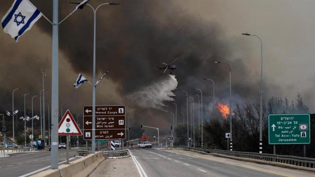 Un helicóptero participa en la extinción de incendios forestales, provocados por el calor y los vientos extremos, que estallaron en el centro de Israel, cerca de Latrún.