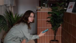 Una trabajadora con un teléfono móvil en la mano espera en el interior de una cafetería de Barcelona durante el apagón del 28 de abril.