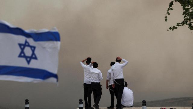 La gente observa el humo mientras estallan incendios forestales en el centro de Israel , en Neve Ilan.