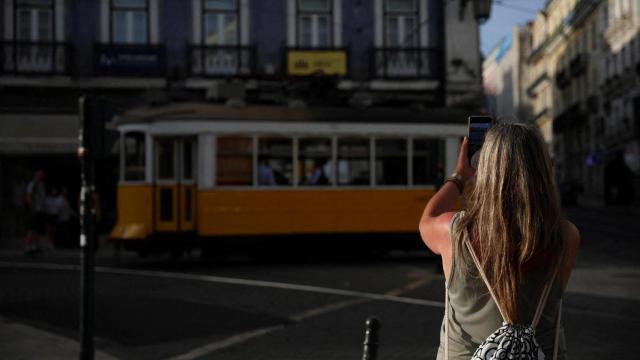 Una persona sostiene un teléfono móvil frente a un tranvía estacionado en la calle durante el corte de energía del lunes en Lisboa.