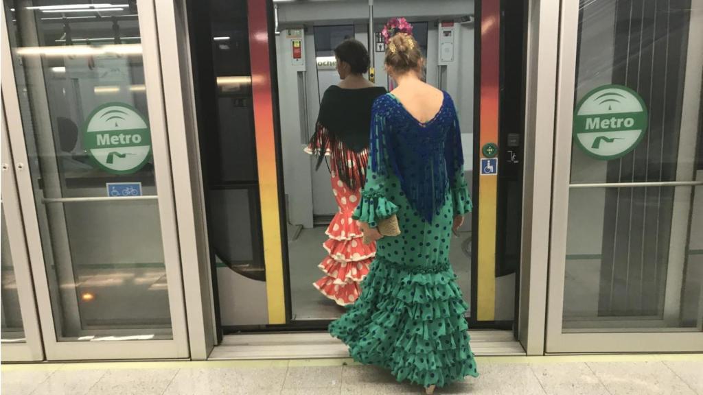 Mujeres vestida de flamenca entrando en el Metro camino a la Feria de Abril.