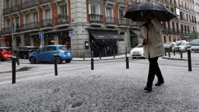 Una mujer se protege de una granizada en Madrid.