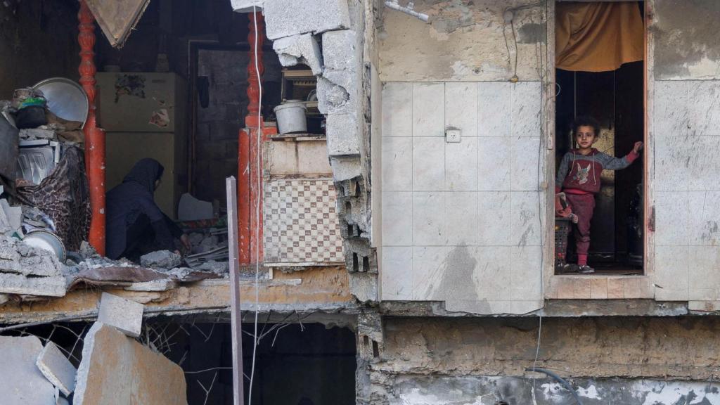 Un niño mira mientras los palestinos inspeccionan el lugar de un ataque israelí contra una casa, en Khan Younis, en el sur de la Franja de Gaza, 3 de mayo de 2025.