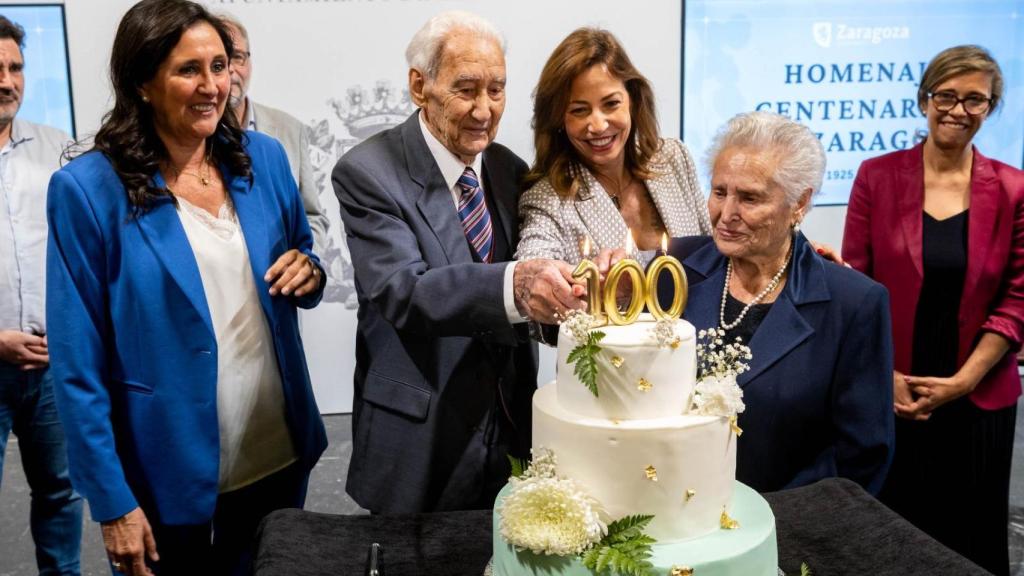 La alcaldesa de Zaragoza, Natalia Chueca, durante el acto, acompañada por dos de los ciudadanos centenarios.