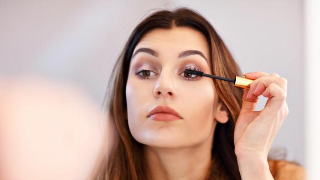 Mujer maquillándose frente al espejo.