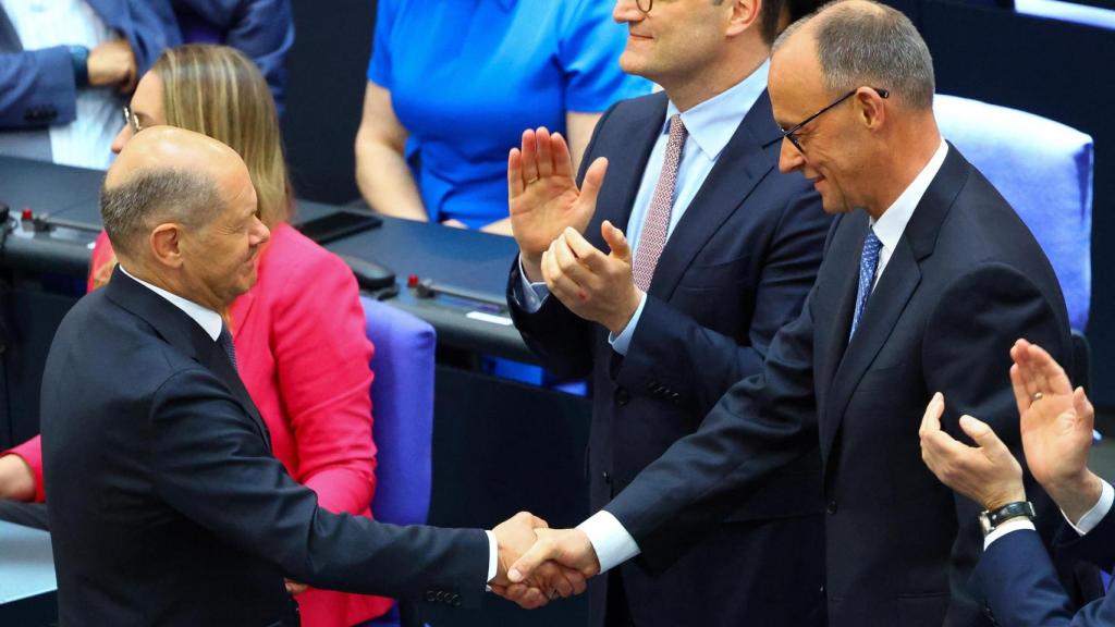 El canciller saliente,  Olaf Scholz, saluda al nuevo jefe de Gobierno alemán, Friedrich Merz, este martes en el Bundestag tras su elección en segunda votación.