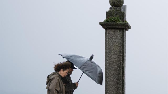Dos personas se refugian de la lluvia con paraguas en la comarca de O Salnés.