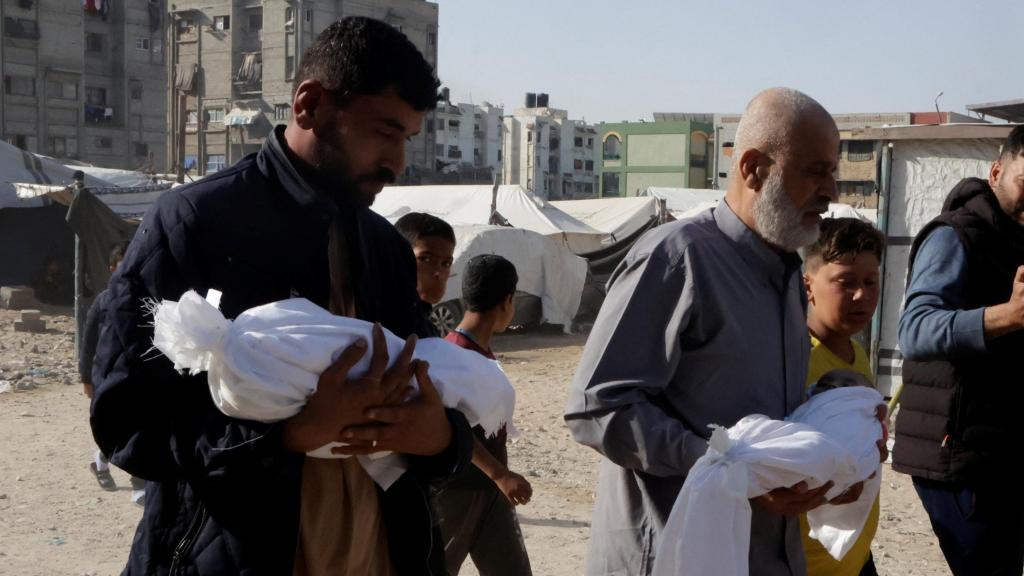 Dos gazatíes cargan con los cadáveres de sus hijos tras un ataque de Israel en Gaza.