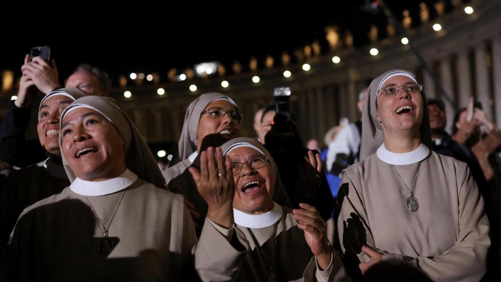 Un grupo de monjas espera expectante a que salga el humo de la chimenea del Vaticano.