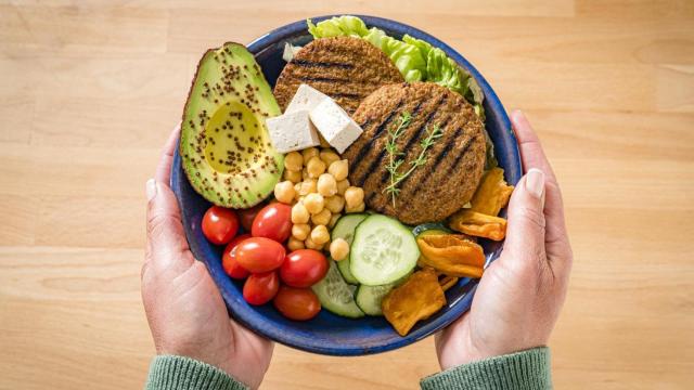 Una mujer sostiene un plato con comida de origen vegetal.