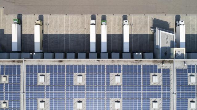 Vista panorámica de camiones descargando en un polígono industrial con techos solares.