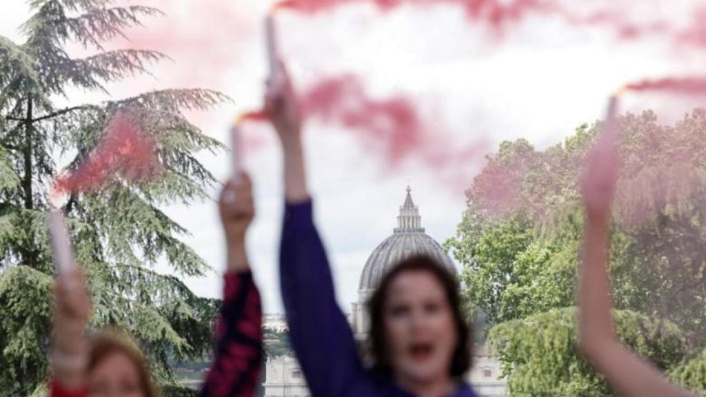 Activistas católicas lanzan columnas de humo fucsia como señal de protesta por la desigualdad.
