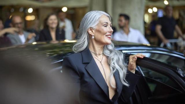 Mujer de pelo cano bajando de un coche.