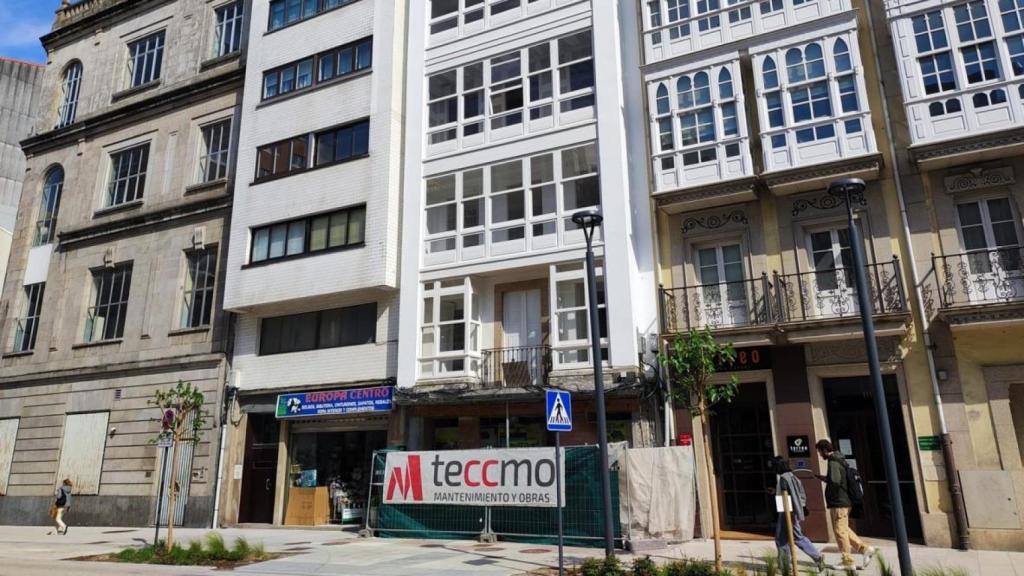 Edificio de viviendas rehabilitado, con valla delante, en la calle San Andrés.