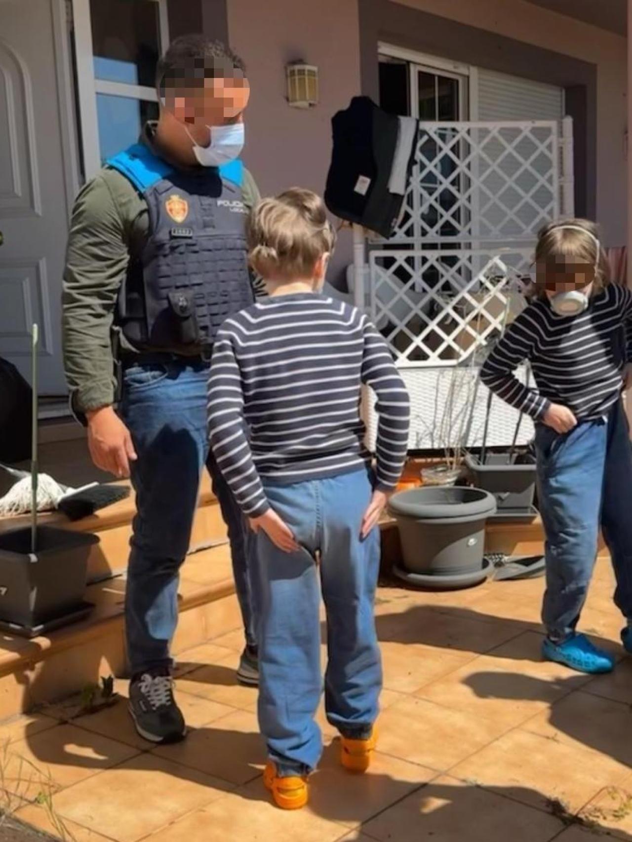 Un policía local de Oviedo junto a dos de los hijos del matrimonio cuando los rescataron de la 'casa de los horrores' el lunes 28 de abril.