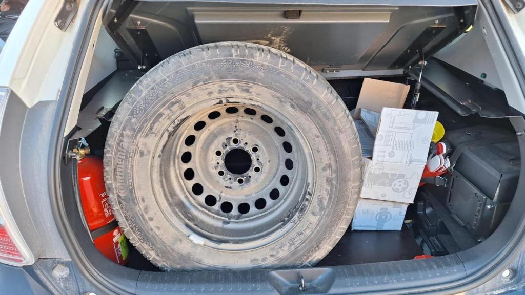 La rueda de repuesto de uno de los furgones, en el maletero de un coche escoba de la Policía.