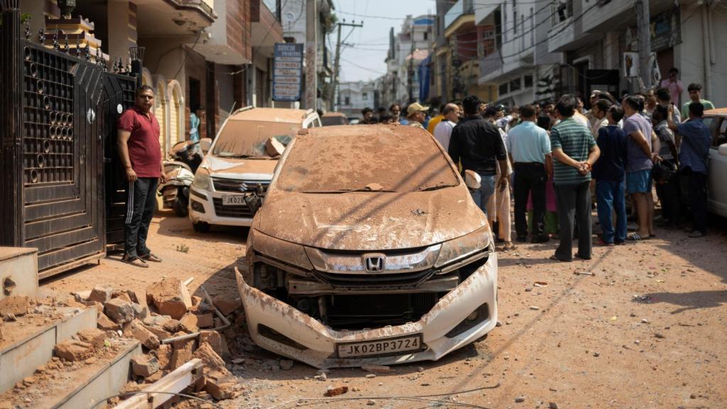Un grupo de personas observa un coche dañado tras la operación militar de Pakistán contra India, en Rehari Jammu.