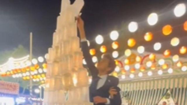 Un niño trata de colocar una de las últimas jarras en una pirámide en plena Feria de Sevilla.