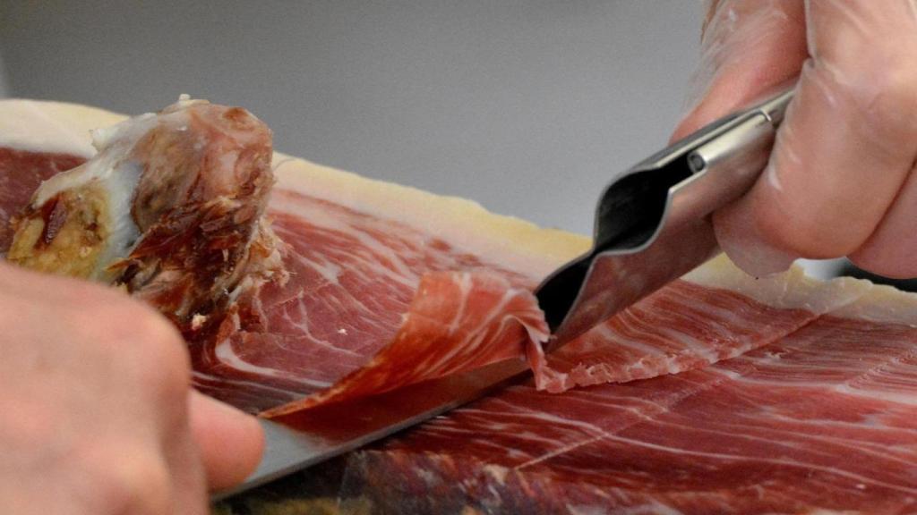 Una persona cortando jamón ibérico