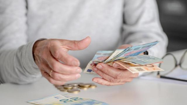 Primer plano de una mujer mayor sujetando billetes de euro.