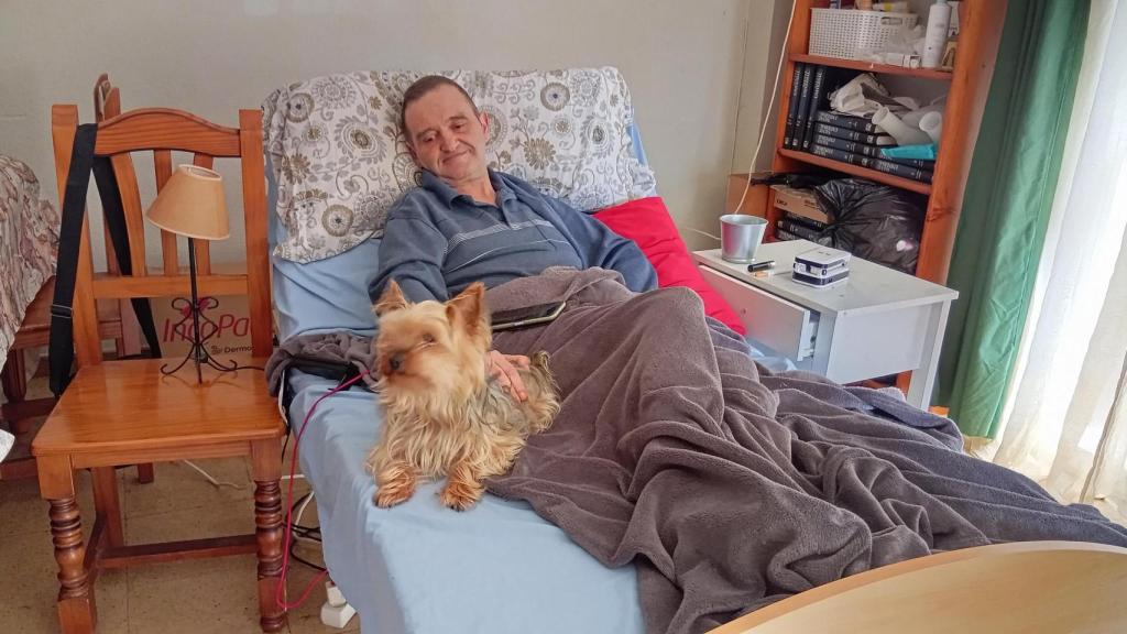 Jesús, en el salón de su casa con su perra Kira.