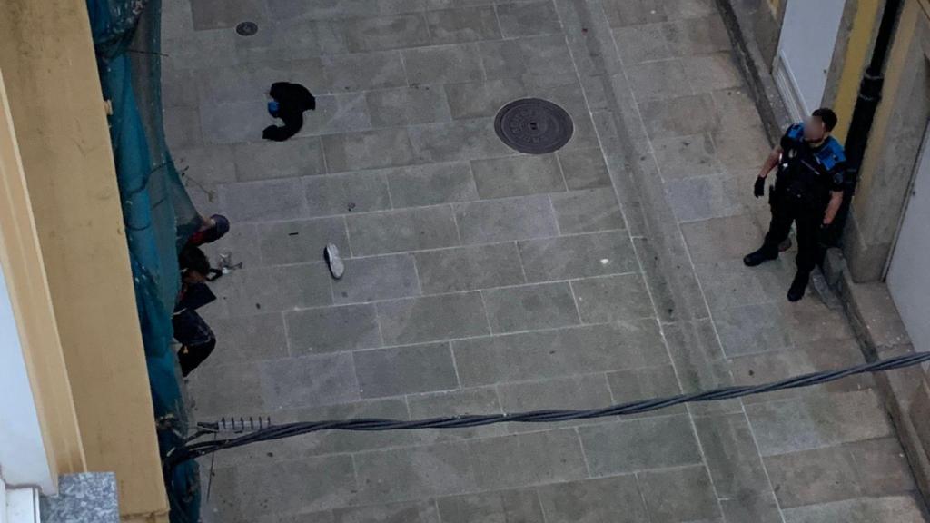 Un okupa encaramado a la fachada de un edificio y la policía solicitando que baje, en A Coruña