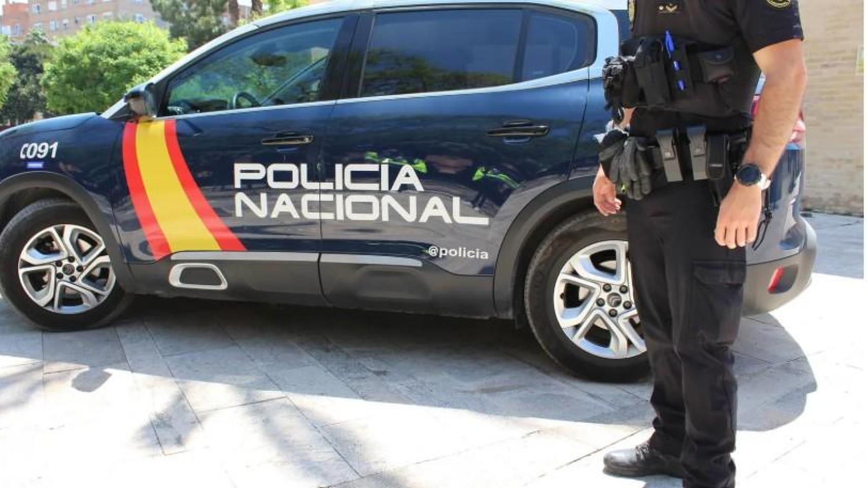 Un agente junto a un coche patrulla de la Policía Nacional en una imagen de archivo.
