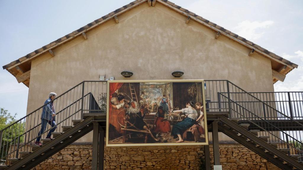 Una persona pasa ante el cuadro de Diego Velázquez Las hilanderas o La fábula de Aracne en una de las poblaciones afectadas por la dana. Efe / Biel Aliño