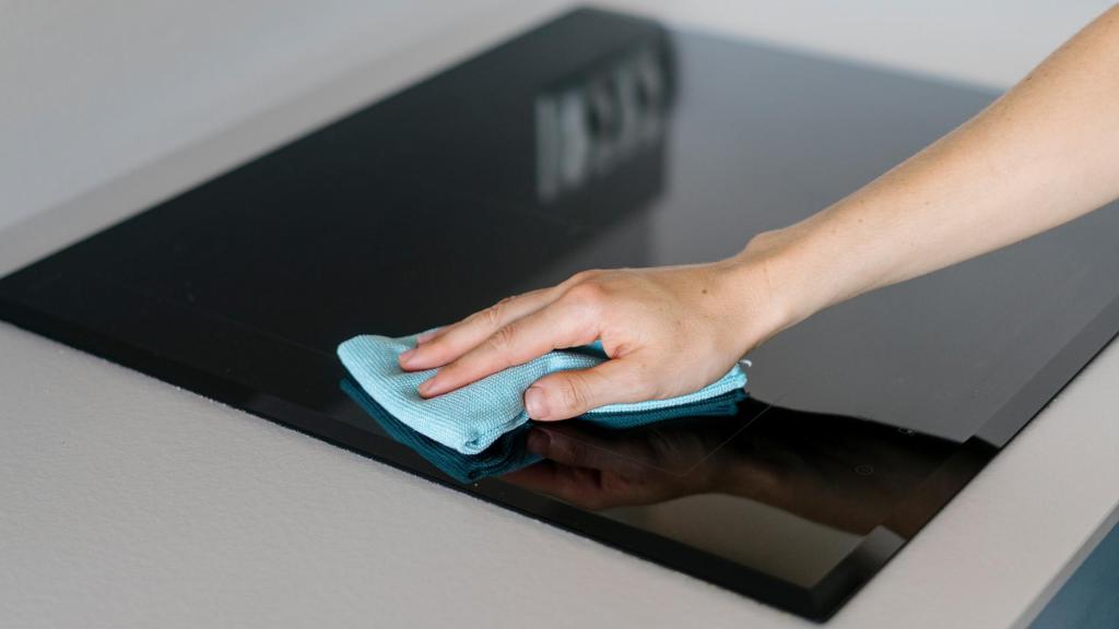 Una persona limpia la vitrocerámica con un paño.