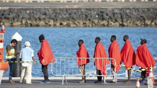 Un agente registra en el puerto de Arrecife (Lanzarote) a 88 migrantes subsaharianos rescatados por Salvamento Marítimo en dos pateras.
