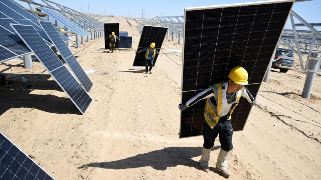 trabajadores transportan paneles solares para instalarlos en una granja solar en Lingwu.