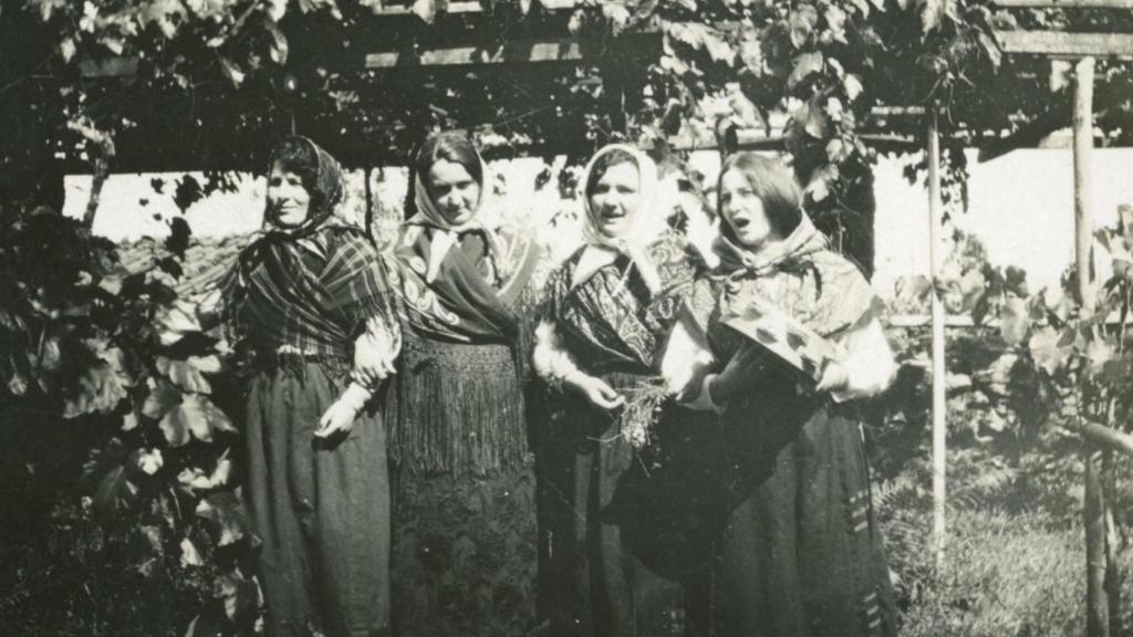 Retrato grupal de cuatro mujeres vestidas con indumentaria tradicional bajo unas vides.