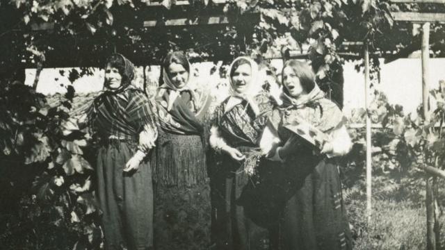 Retrato grupal de cuatro mujeres vestidas con indumentaria tradicional bajo unas vides.