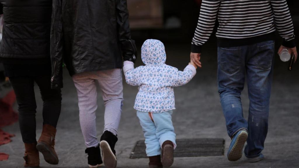 Imagen de archivo de un menor de la mano de sus padres.