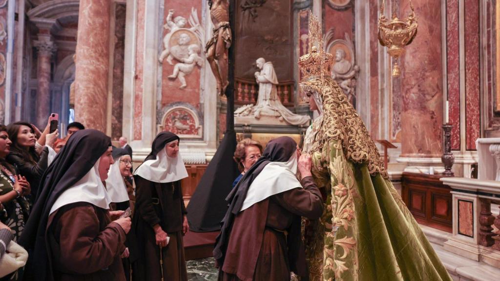 Unas monjas besan la mano de la Virgen de la Esperanza.