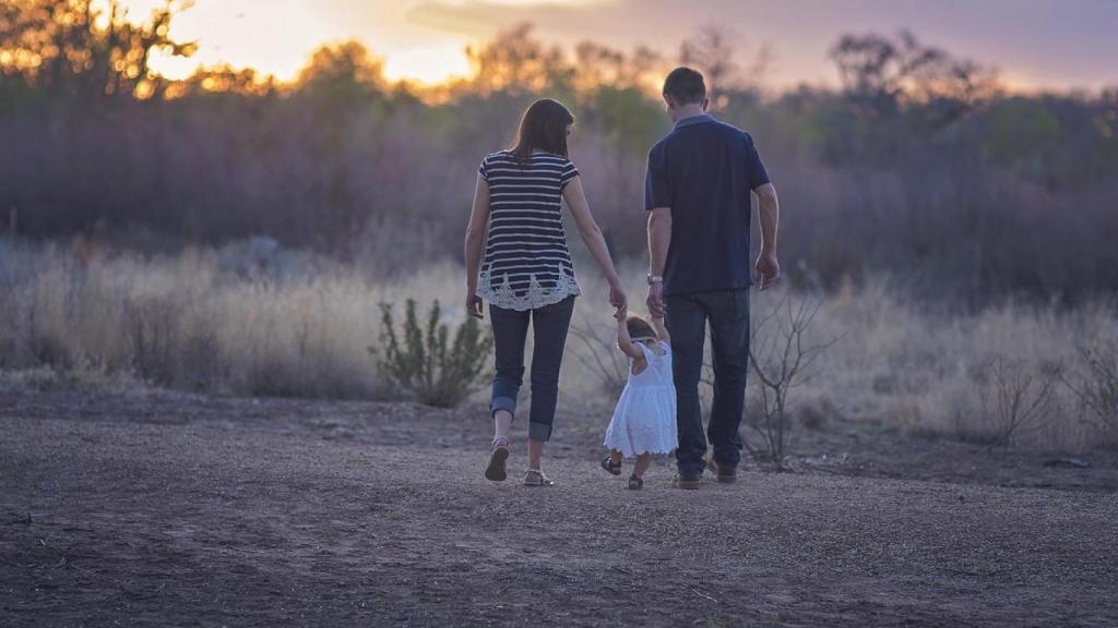 Una familia caminando con su hija pequeña.