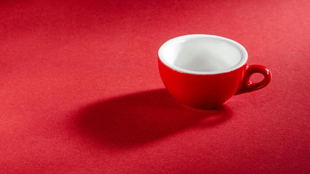 Una taza de café sobre fondo rojo.